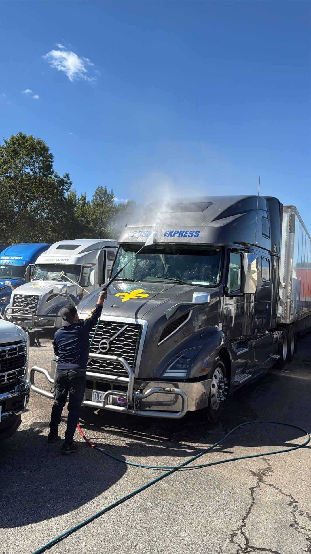 Sunset technician pressure washing a commercial Volvo semi-truck on a client's fleet route